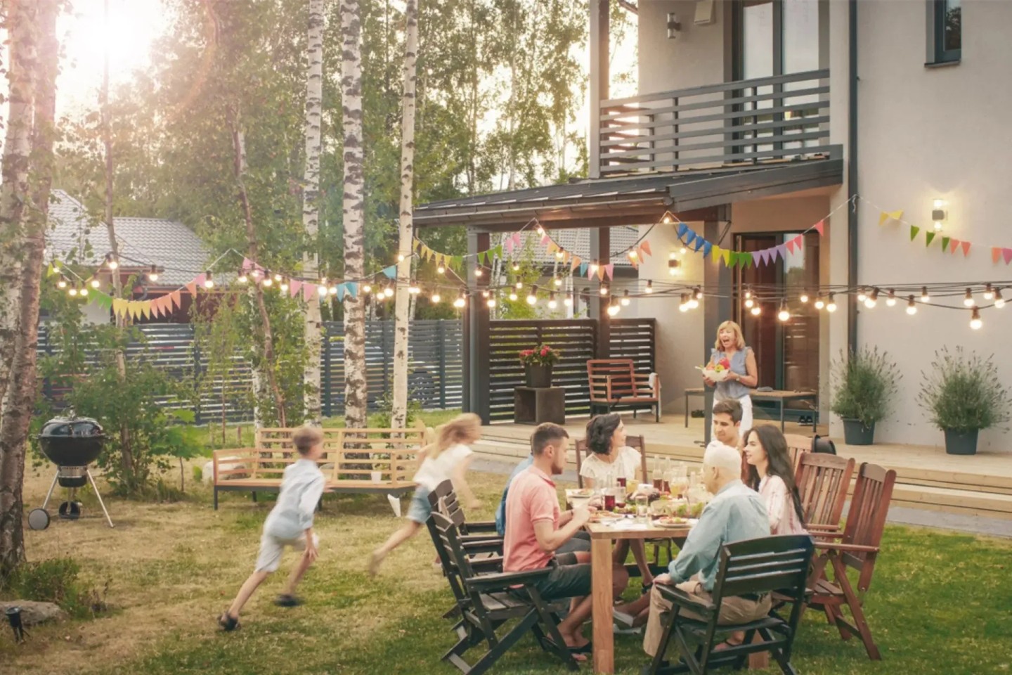 Eine Familie sitzt am Tisch und grillt. Kinder laufen drumherum. Die Eigentümer haben einen Teilverkauf durchgeführt.