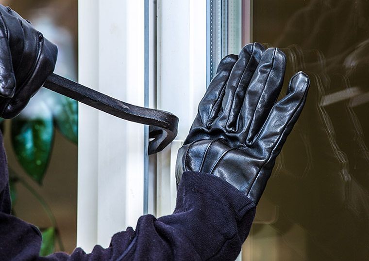 Einbrecher brechen mit einem Kuhfuss ein Fenster auf