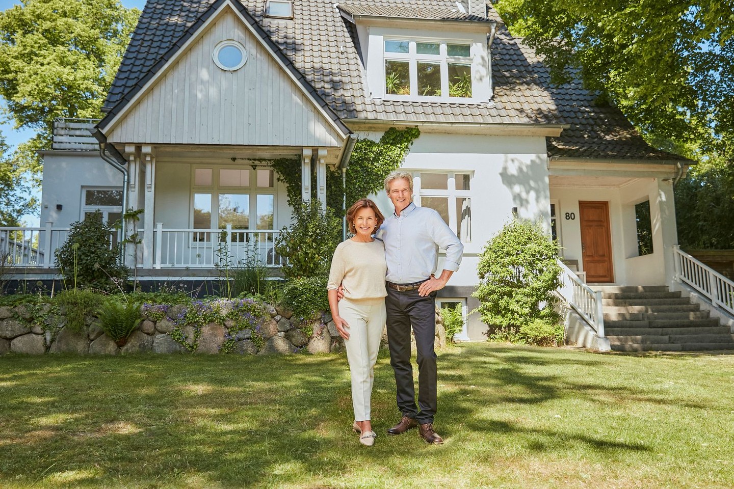 Zwei Kunden stehen vor ihrer Immobilie. Sie haben einen Teilverkauf durchgeführt.