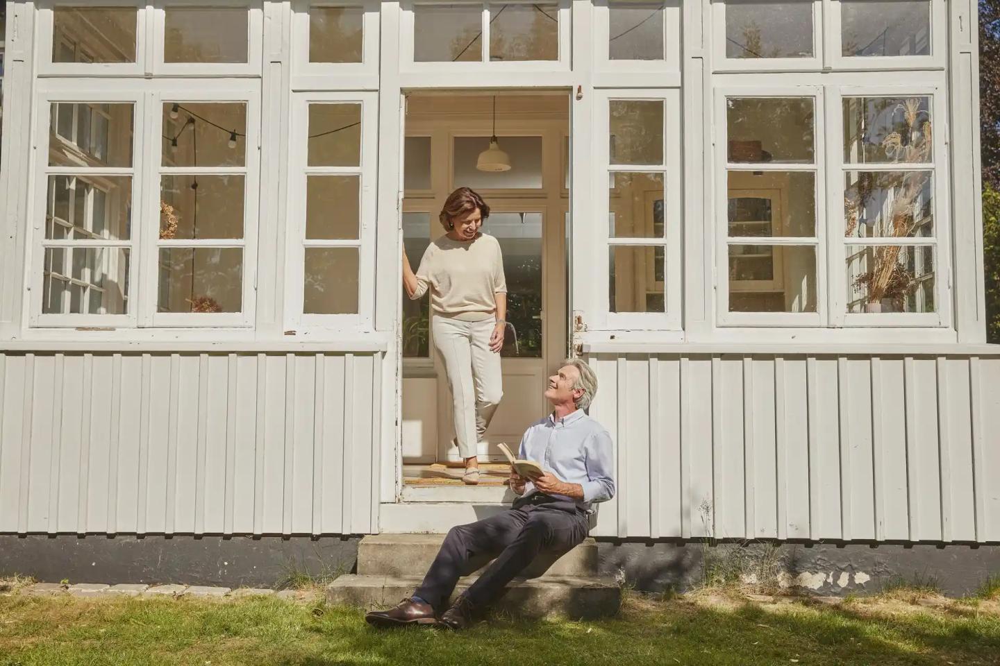 Ein Paar im Rentenalter unterhält sich vor Ihrer Hausveranda.