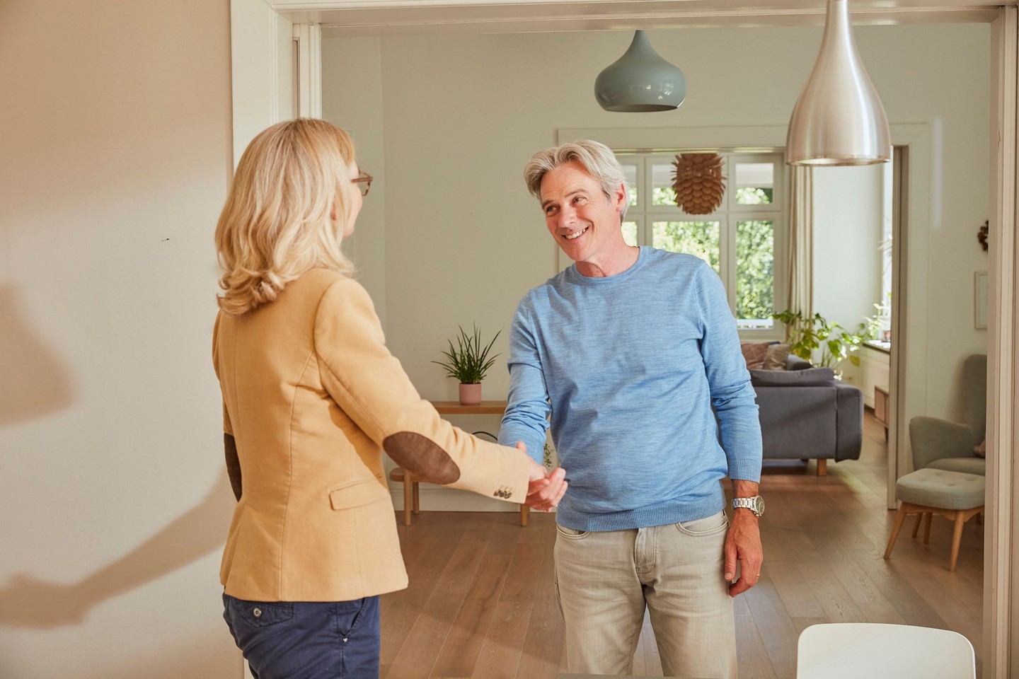 Eine Kundenberaterin gibt ihrem Kunden die Hand.