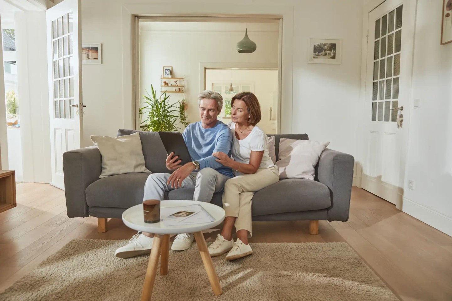 Ein Ehepaar sitzt auf dem Sofa. Sie schauen sich auf dem iPad alles über den Teilverkauf