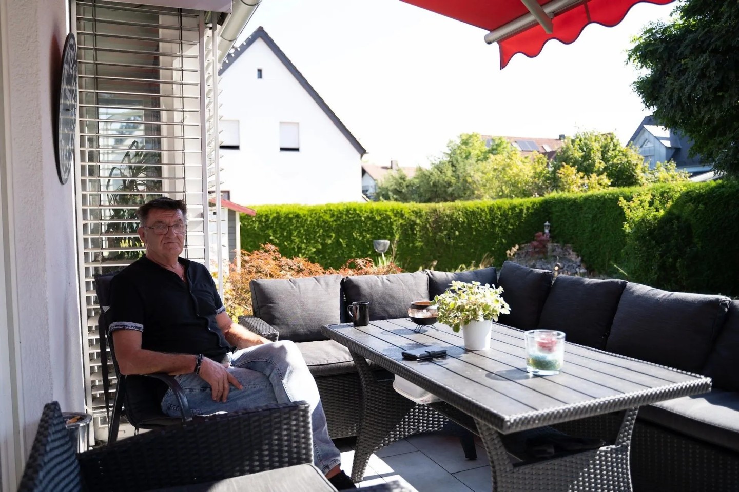 Ein Kunde sitzt auf seiner Terrasse vor seiner Immobilie. Er hat einen Teilverkauf durchgeführt.