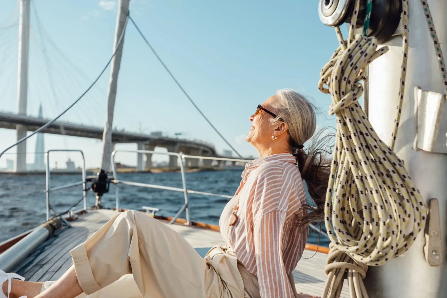 Eine Frau sitzt auf einem Segelboot und genießt ihre Frührente.
