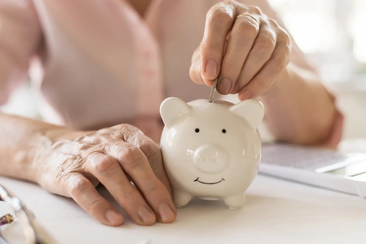 Eine Frau wirft Geldmünzen in ein Sparschwein weil sie Geld sparen möchte.
