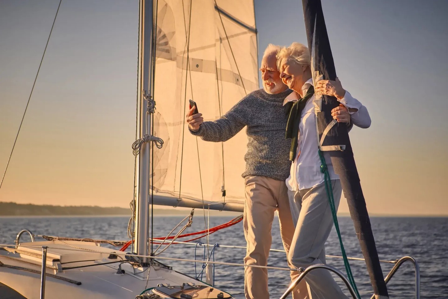 Ein Ehepaar steht auf einem Segelboot und machen ein Selfie. Sie genießen ihren Ruhestand.