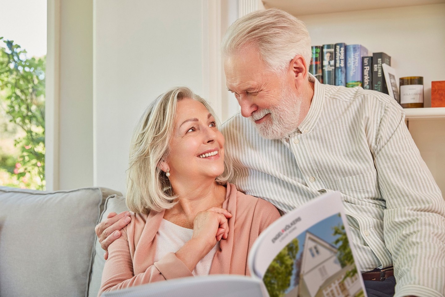 Ein älteres Ehepaar blickt sich verliebt an. Sie haben eine Broschüre in den Händen.