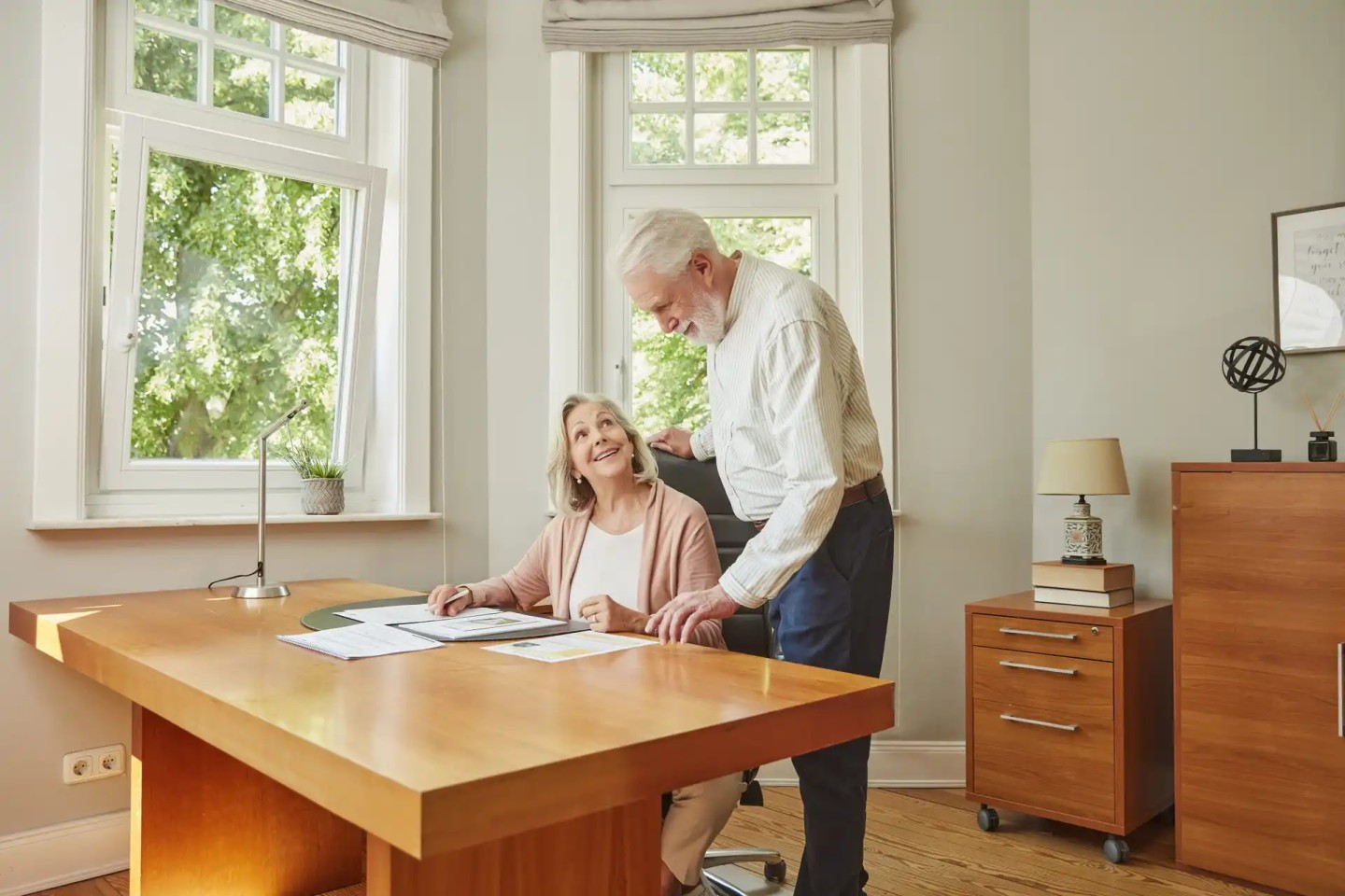 Ein Paar im Rentenalter unterhält sich an einem Tisch über Unterlagen.