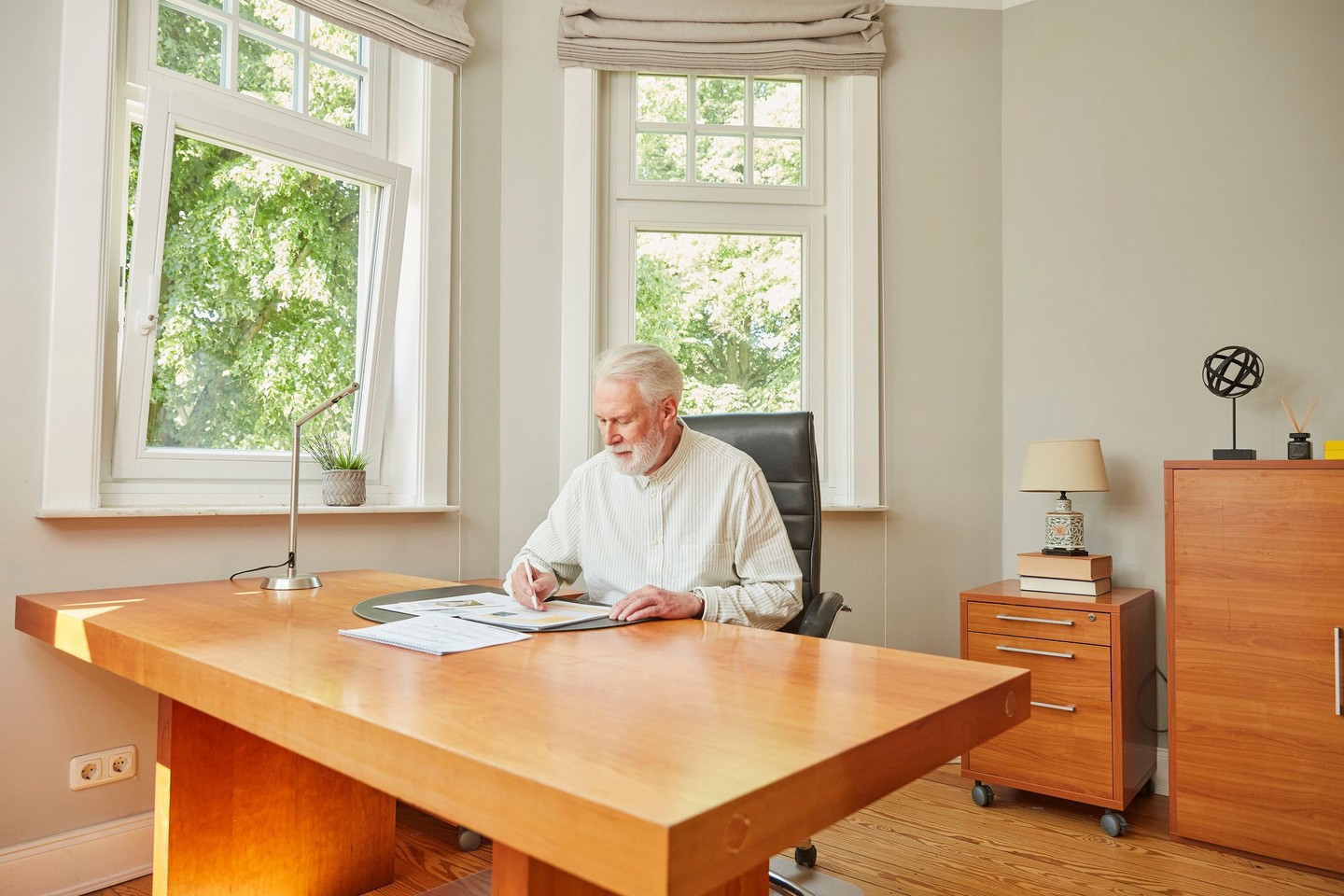 Ein Mann sitzt am Schreibtisch und blättert durch Dokumente.