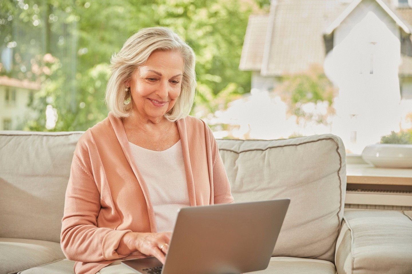 Eine Frau sitzt auf dem Sofa und arbeitet am Laptop.