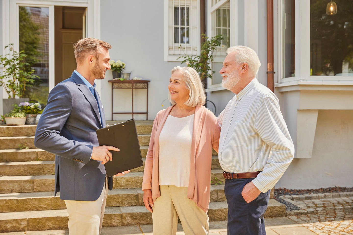 Ein Kundenberater steht mit zwei Kunden vor der Immobilie und spricht über den Teilverkauf.