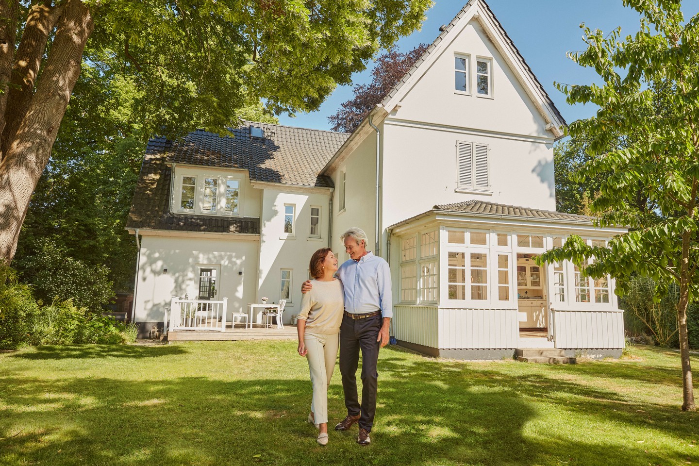 Ein Ehepaar steht im Garten vor ihrem Haus