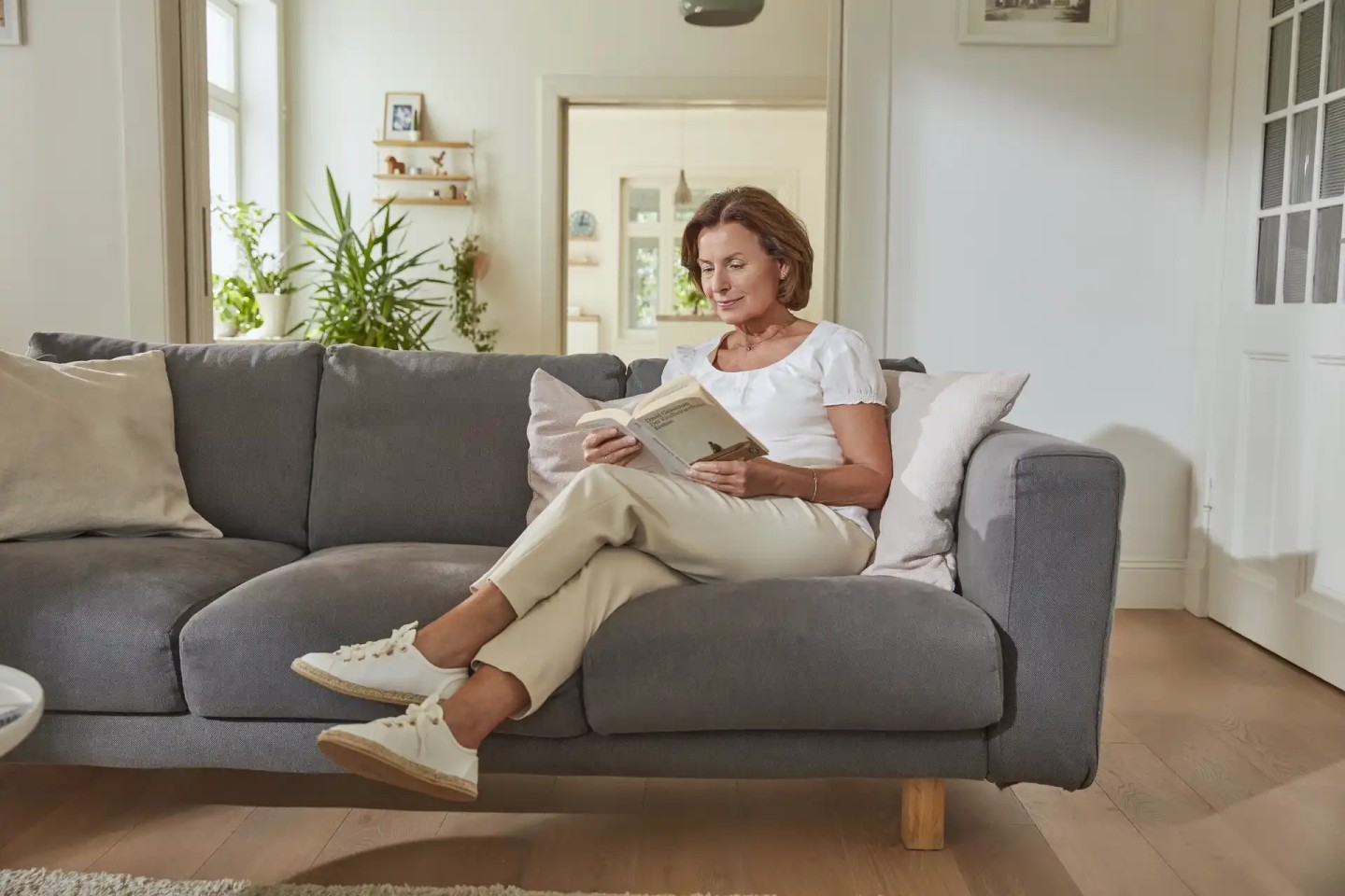 Eine Frau im Rentenalter sitzt auf der Couch uns liest.