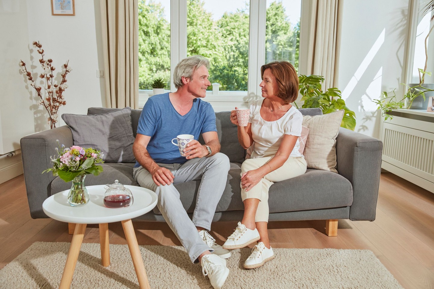 Ein Ehepaar sitzt auf dem Sofa und trinkt Tee.