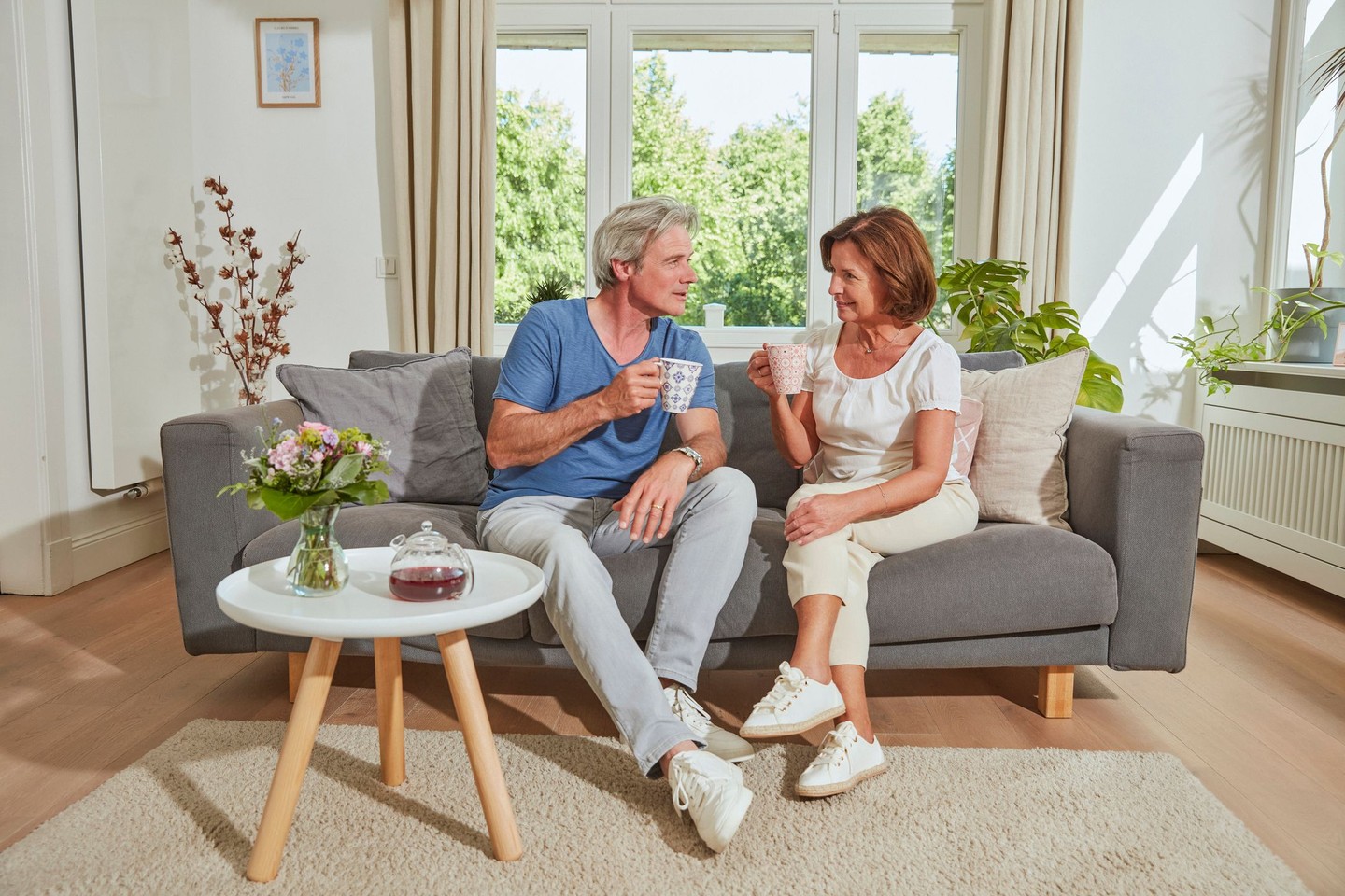 Zwei Kunden sitzen auf ihrem Sofa und trinken Tee.