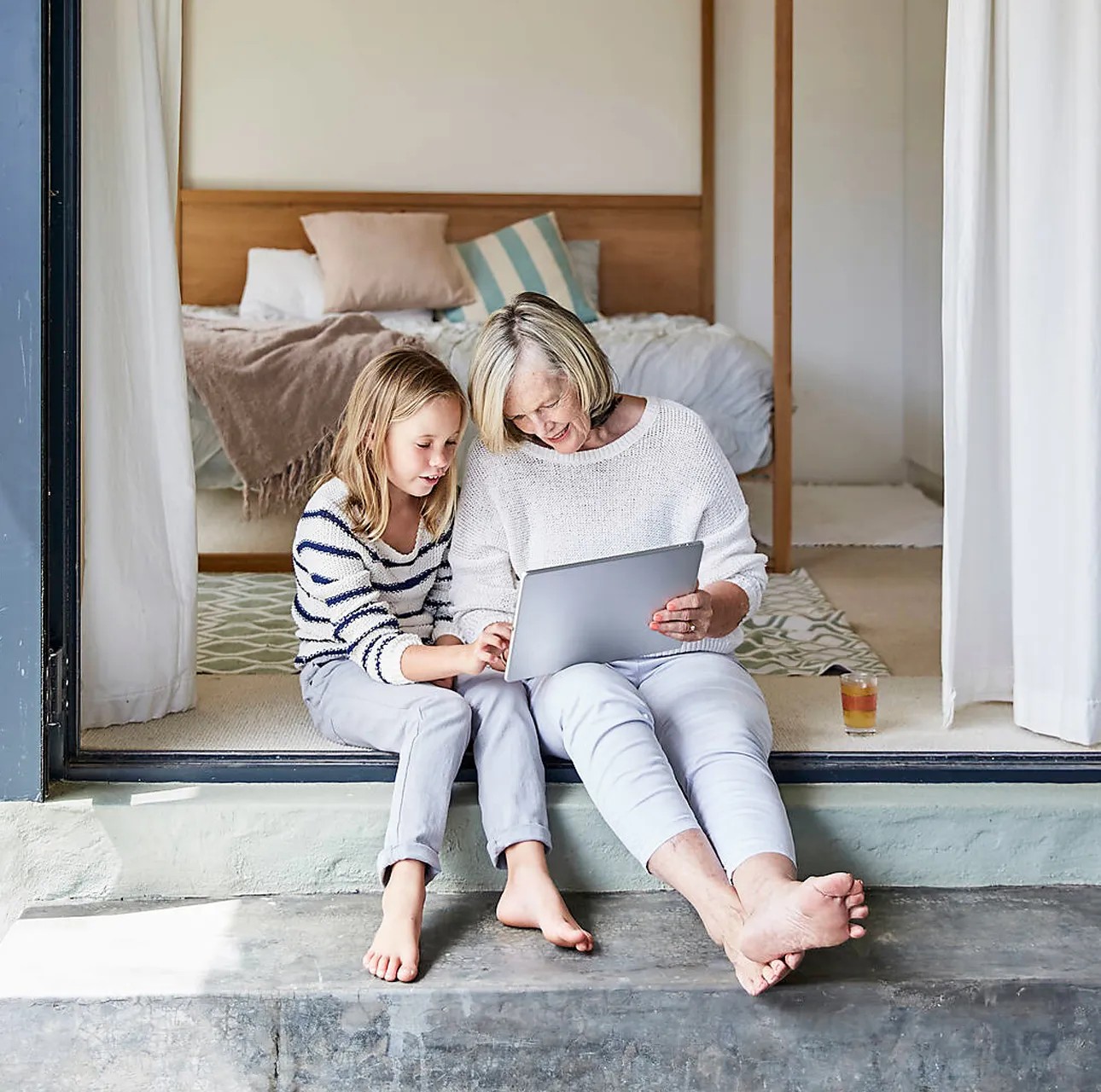 Großmutter und Enkelin sitzen nebeneinander und sehen sich etwas an