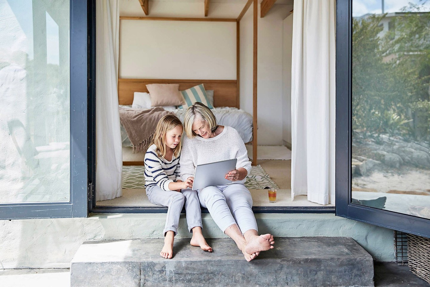 Großmutter und Enkelin sitzen nebeneinander und sehen sich etwas an