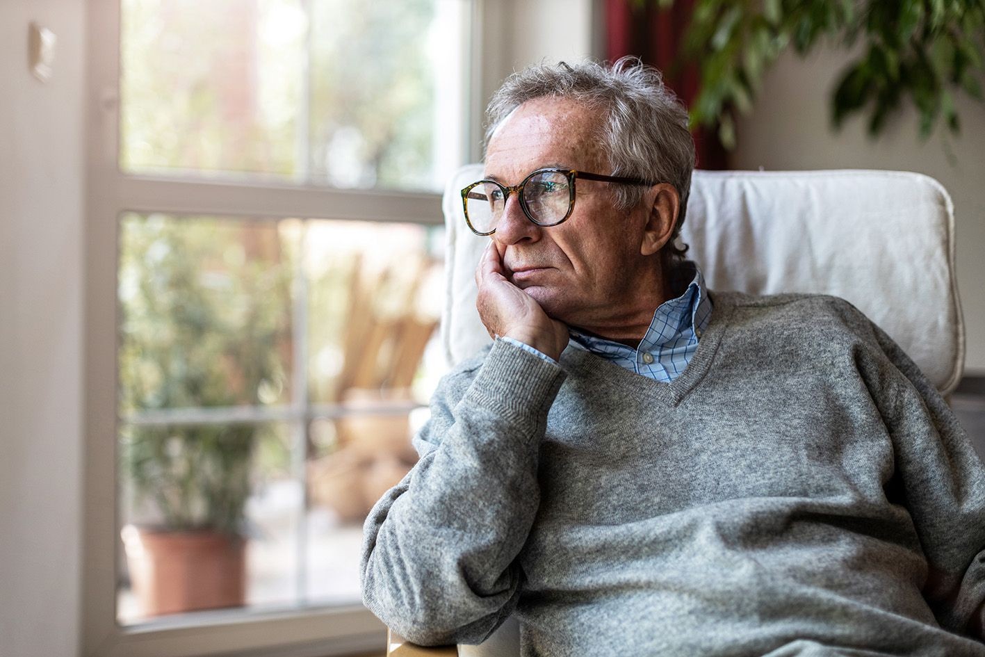 Mann guckt nachdenklich aus dem Fenster