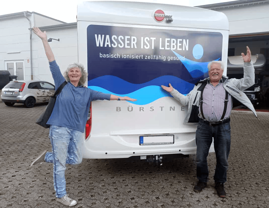 Ehepaar Jaekel steht vor dem Wohnwagen und freut sich