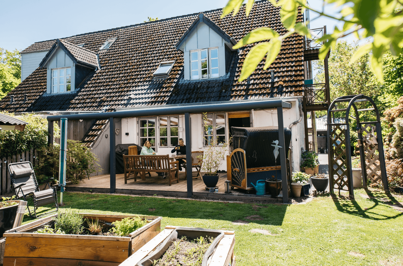 Familie D. sitzen vor ihrem Haus auf der Terrasse