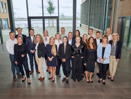 Das Customer Care Team von Engel & Völkers LiquidHome steht in der Eingangshalle des Büros.