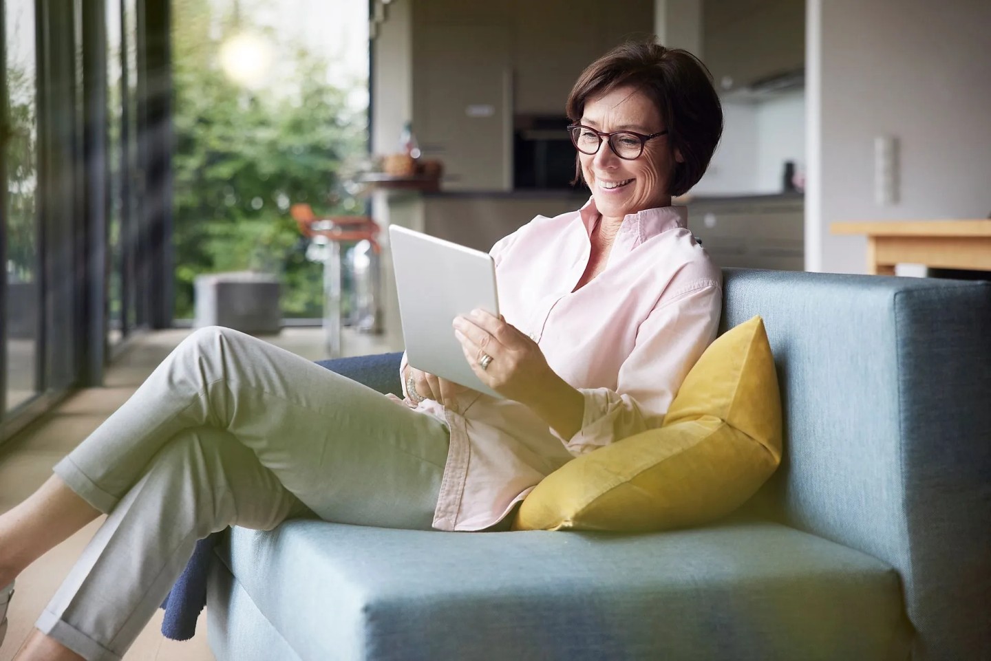 Eine Frau sitzt auf einem Sofa am iPad und plant einen Zweitwohnsitz zu kaufen.